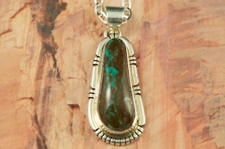 Genuine Sunnyside Turquoise set in Sterling Silver Pendant. Created by Navajo Artist Lucy Valencia. Signed LJ. The matrix on this rare stone is outstanding. The Sunnyside mine is located in northern Nevada near the town of Tuscarora in the Tuscarora mountain range. Free 18 inch Sterling Silver Chain with purchase of pendant.